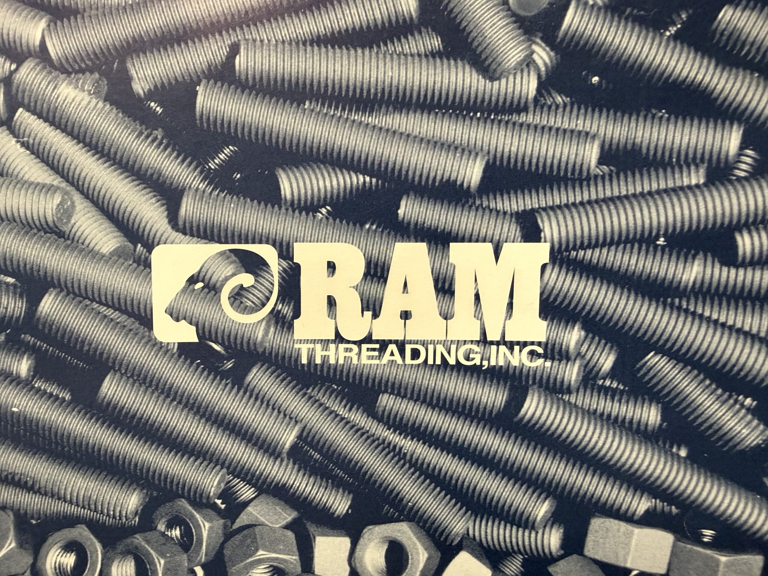 RAM Threading logo displayed over a background of industrial stud bolts